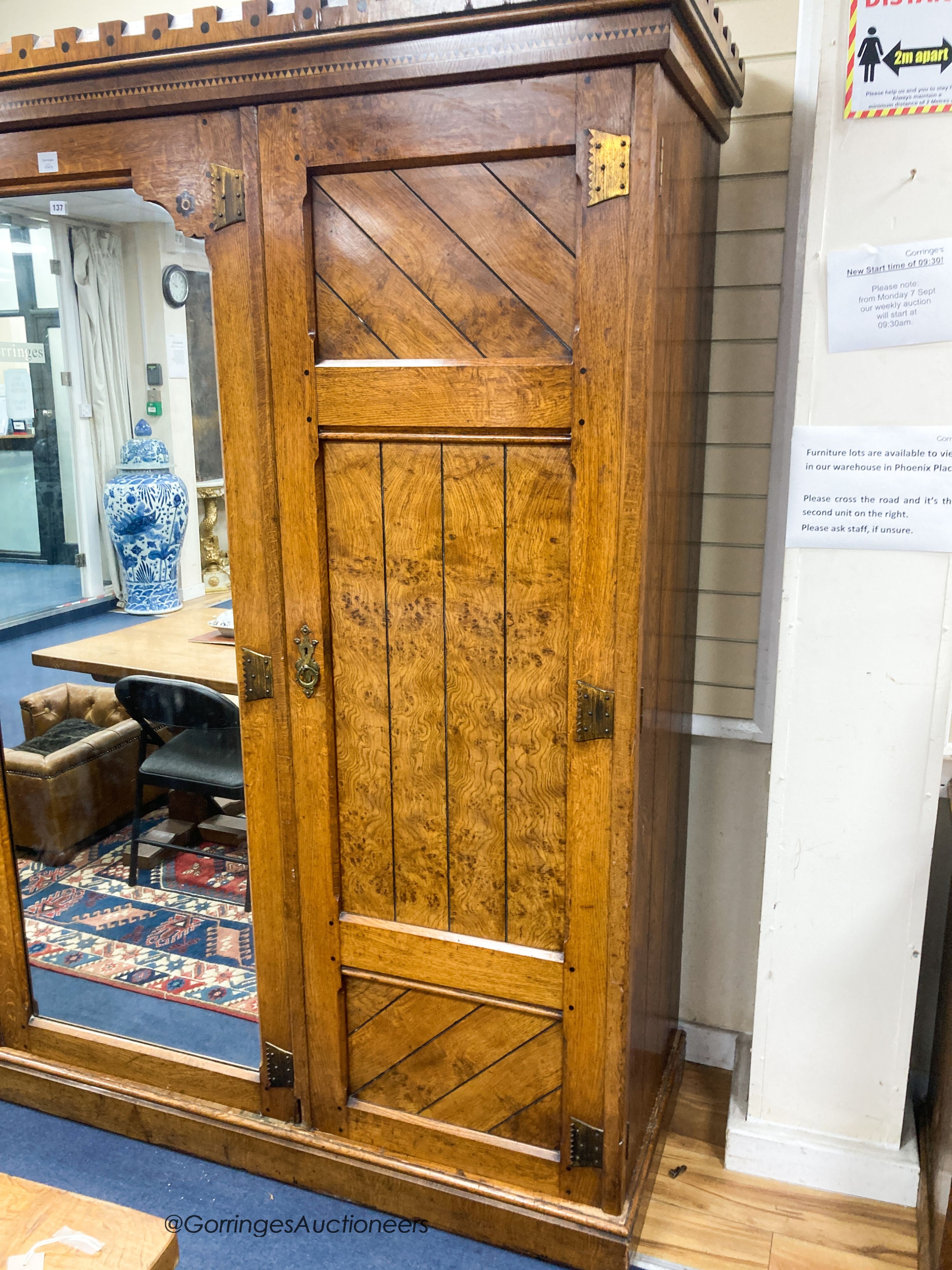 A late Victorian inlaid oak and pollard oak Aesthetic movement three door mirrored wardrobe by Garnett & Son, Warrington, length 216cm, depth 64cm, height 213cm